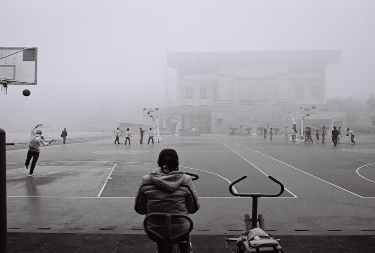 A student reading alone beside a foggy school playground