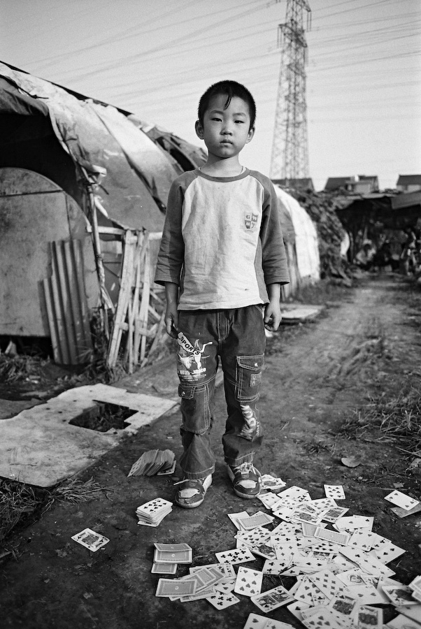 A boy standing among scattered playing cards in a settlement