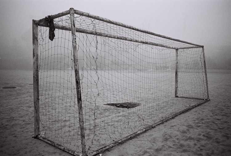 An empty football goal on a foggy field